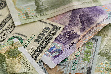 Chinese Five Yuan Banknote Layered on US One Hundred Dollar Bill Background