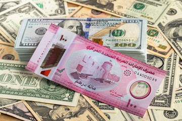 UAE One Hundred Dirham Banknote on Stack of US One Hundred Dollar Bills