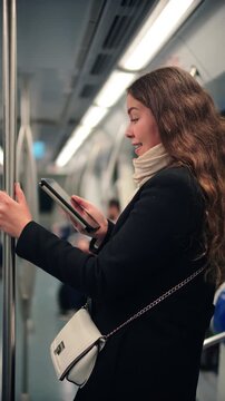 A young woman is deeply focused on reading an ebook on her device while commuting on the subway, making the most of her time during the travel, showcasing the joy of reading on the go.