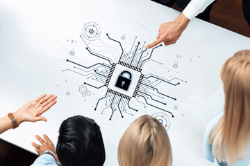A diverse group of professionals engages in a discussion about cybersecurity concepts, analyzing digital designs on a table while focusing on data protection strategies and innovations. Trope