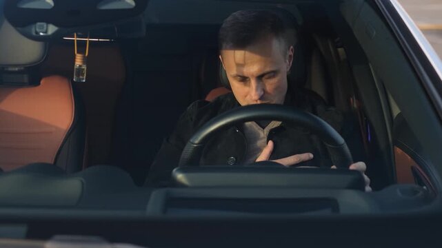 Male driver clutching his heart while driving a car, view through the glass