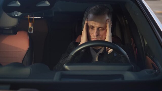A tired driver massages his temples with his eyes closed, preparing for the journey