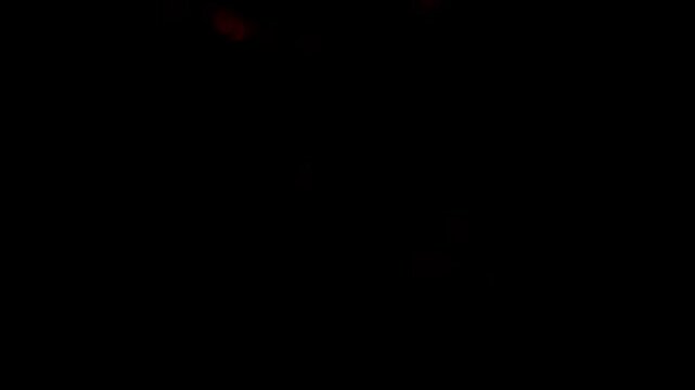 This abstract video features a dynamic interplay of vibrant red bokeh lights against a deep black background. Numerous glowing orbs of varying sizes create a sense of depth and movement