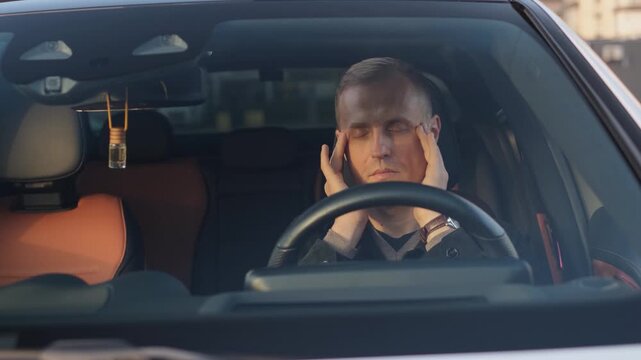 A tired driver massages his temples with his eyes closed, preparing for the journey