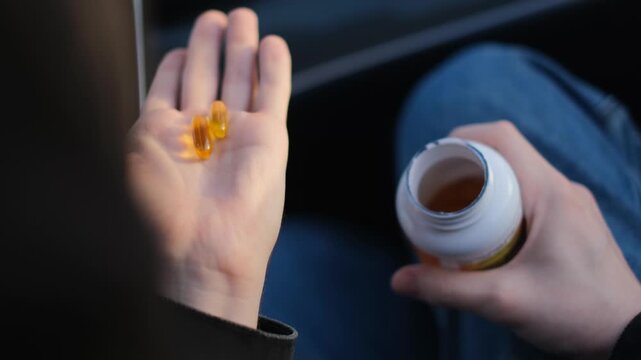 A man holds omega 3 fatty acid capsules in his palm, close-up