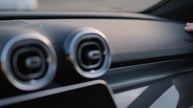 A man evaluates the quality of a car's dashboard by touching it with his hand