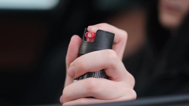 A close-up of a man holding a canister of pepper spray