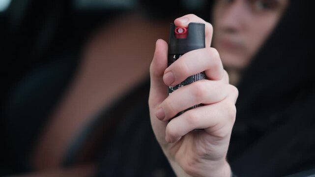 A male driver holds a canister of tear gas in his hands
