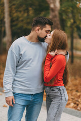 Fototapeta premium youthful pair with bright autumn backdrop, smiling duo dressed in colorful attire amidst fall scenery