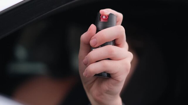 A close-up of a man holding a canister of pepper spray
