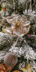 Elegant white flower decoration on snowy Christmas tree branch with glitter details. Selective focus