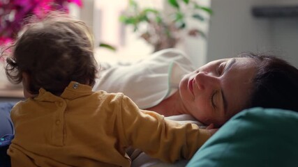 Mother relaxing on sofa with toddler leaning close sharing soft affectionate interaction that conveys trust emotional warmth and quiet tender bonding inside calm home environment