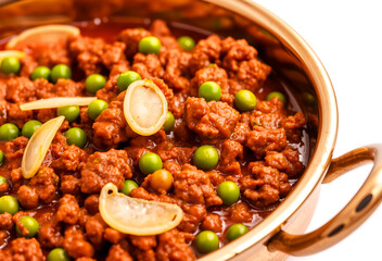 traditional indian keema matar curry in copper bowl