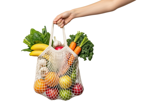 A female hand holds a reusable mesh shopping bag full of fresh organic fruits and vegetables like carrots, kale, and apples, isolated on a solid black background - Powered by Adobe
