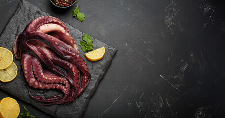 Raw squid or octopus from above, resting on a dark slate board, with fresh lemon slices and peppercorns for cooking preparation space for text