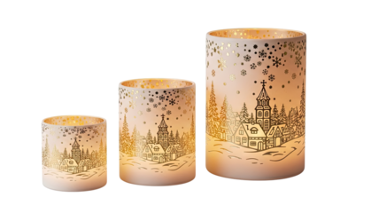 Three glowing decorative candle holders of varying sizes illuminate a charming golden winter village scene with houses, trees, and a church, adorned with delicate snowflakes