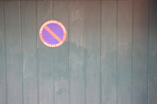 French &ldquo;Stationnement Interdit Jour et Nuit&rdquo; (&ldquo;No parking day and night&rdquo;) sign mounted on a textured green wall.