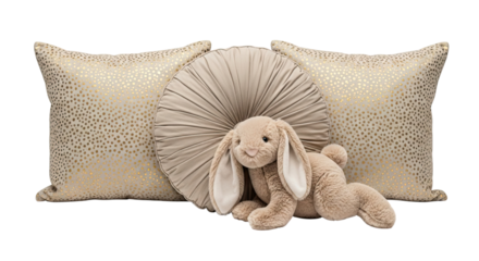 A cute beige plush bunny rabbit toy with long floppy ears rests against elegant decorative pillows with gold polka dots, isolated on a black background for a cozy nursery concept