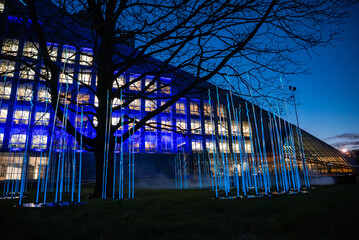 Vertical blue light rods glow under bare branches before the National Library of Latvia in Riga at...