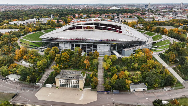 Telephoto side view of the west side of RB Leipzig Arena, modern stadium in the shape of the former Zentralstadion, city center in the background.
