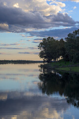 Calm Reservoir Reflection with Dark Tree Line and Cloudy Sunset Sky