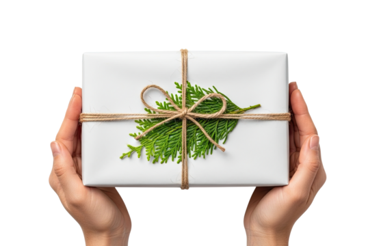 A person's hands hold a simply wrapped white gift box tied with rustic twine and a fresh evergreen sprig, presented against an isolated black background for a special occasion