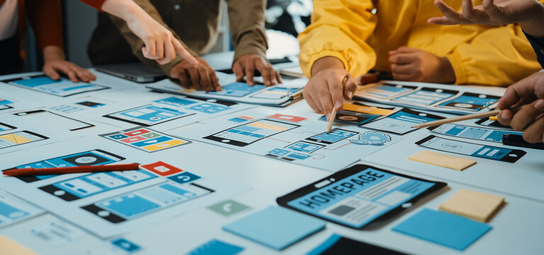 A dynamic design workshop scene showing diverse hands engaged in collaboration, focus on user interface prototyping and app planning, surrounded by visual mockups. SACTR