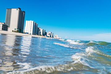 Blue ocean surf and skyline of beachfront highrises on a sunny day