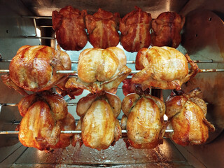 Cooking big batch of rotisserie chicken in large commercial oven. High volume poultry preparation for deli. Plain and staffed product.
