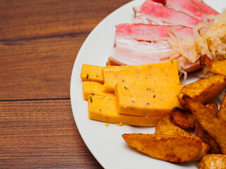 Plate with smoked ham, spicy potato wedges, cheese and sour cabbage. Tasty dish, Big portion of food. Pork meat sliced in fine portions.