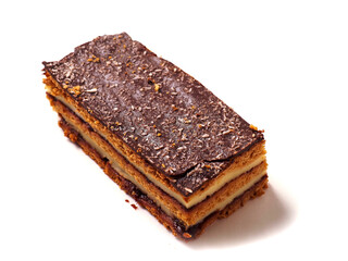 A dessert layered cake with chocolate on top is on white background. The dessert is a cake with a brown crust.