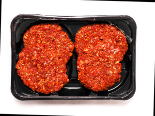 Four fresh burgers on a black plastic tray on white background. Premium beef minced meat. Food supply chain and industry.