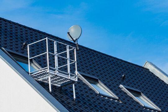 Roof maintenance platform next to satellite dish under blue sky
