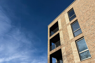 Modern brick building exterior with balconies against blue sky
