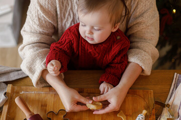 Happy mother with cute baby son making gingerbread christmas cookies together, holding dough in hands close up, top view. Christmas family traditions, winter holiday preparation
