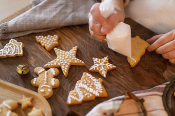 Woman decorating christmas gingerbread cookies flat lay with sugar glaze on rustic table close up. Holiday Family tradition