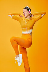 Female fitness enthusiast wearing orange activewear performs a lively dance pose, exuding energy...