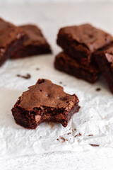 Straight-on view of brownie squares with one bitten brownie in the center and stacked brownies in the background.