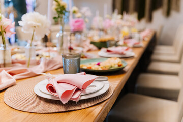 Elegant place setting with pink napkin and floral decor at festive banquet table
