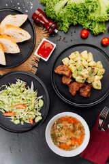 Hearty restaurant lunch: soup, fried meat with potatoes, fresh cabbage salad and bread
