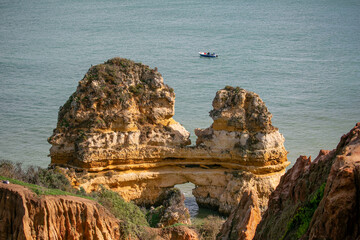 Cliffs on a coastline with a small boat coasting along 
