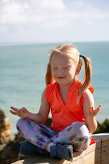 A girl practicing yoga by holding a relaxing yoga posture while enjoying an ocean view