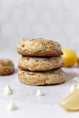 Straight-on view of lemon poppyseed cookies stacked on top of each other with lemon slices and white chocolate chips arranged around them.