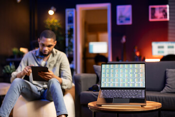 African american guy following the day trading index and trends, laptop running stock market exchange diagram increasing or decreasing. Forex trading visualization on pc display.