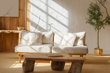 Fotobehang Scandinavisch Bright cozy living room with light beige sofa, rustic wooden coffee table and sunlight streaming through window. Home interior design in scandinavian style with warm tones and natural materials.  © katyamaximenko
