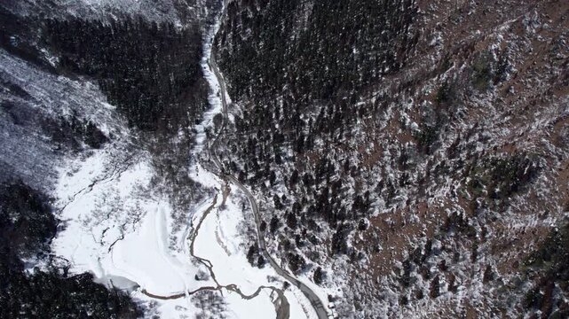 Drone view of snow covered mountains and forests in Bipeng Valley in Sichuan, China in sunny winter day, high angle view of beautiful winter landscape. 4k real time footage, travel concept