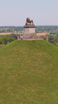 visitors atop stairs platform surrounded by green grass mound lion's waterloo belgium both monument's angle upward drone shot leeuw van lush scale natural 