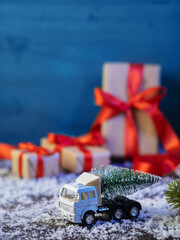 Happy New Year card. A toy truck carries a Christmas tree and gift boxes. Copy space