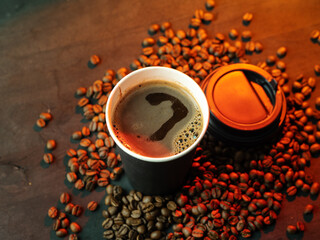 Paper cup of espresso coffee on wooden table with roasted coffee beans