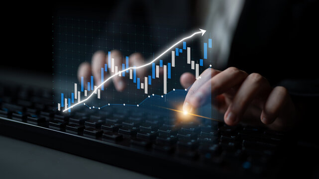 A close-up of hands typing on a keyboard with a digital stock market graph overlay, representing financial analysis, investment growth, and real-time data insights. Impute - Powered by Adobe